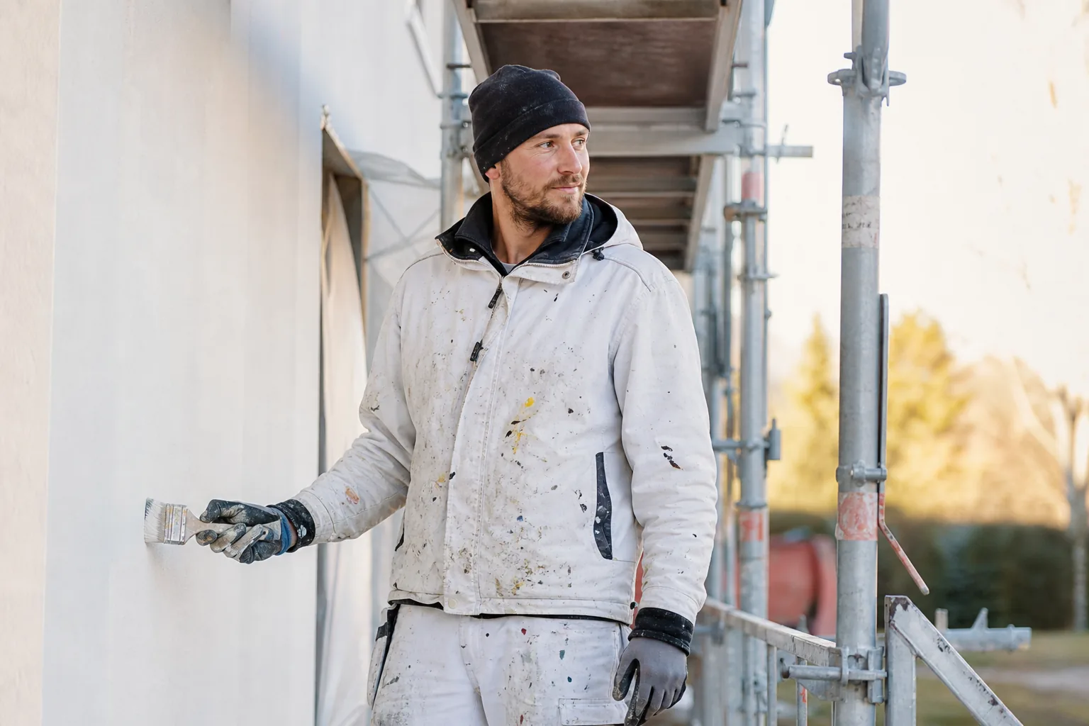 Målare i arbetskläder med färgfläckar vid en ställning
